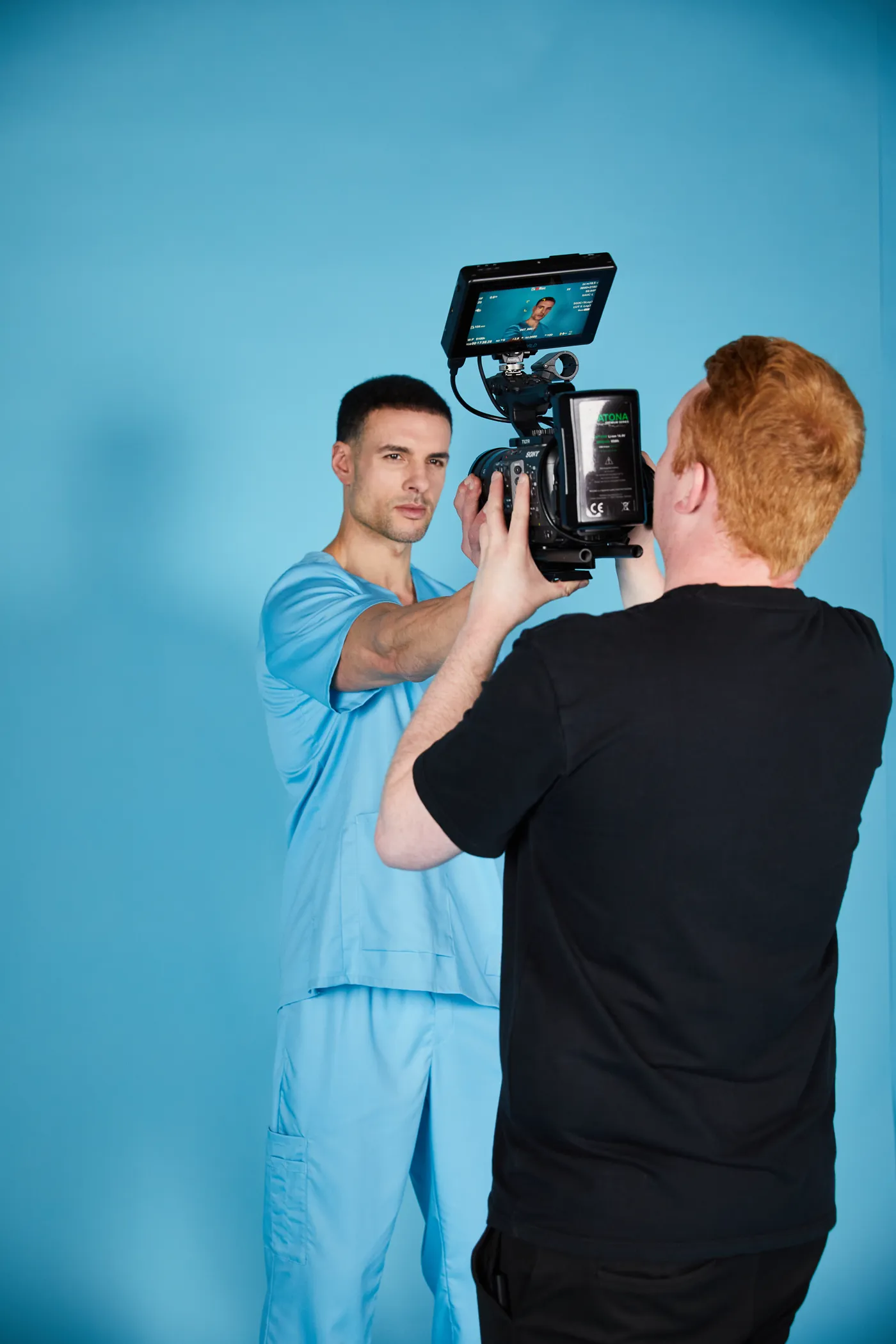Videograf filmt ein männliches Model vor blauem Hintergrund