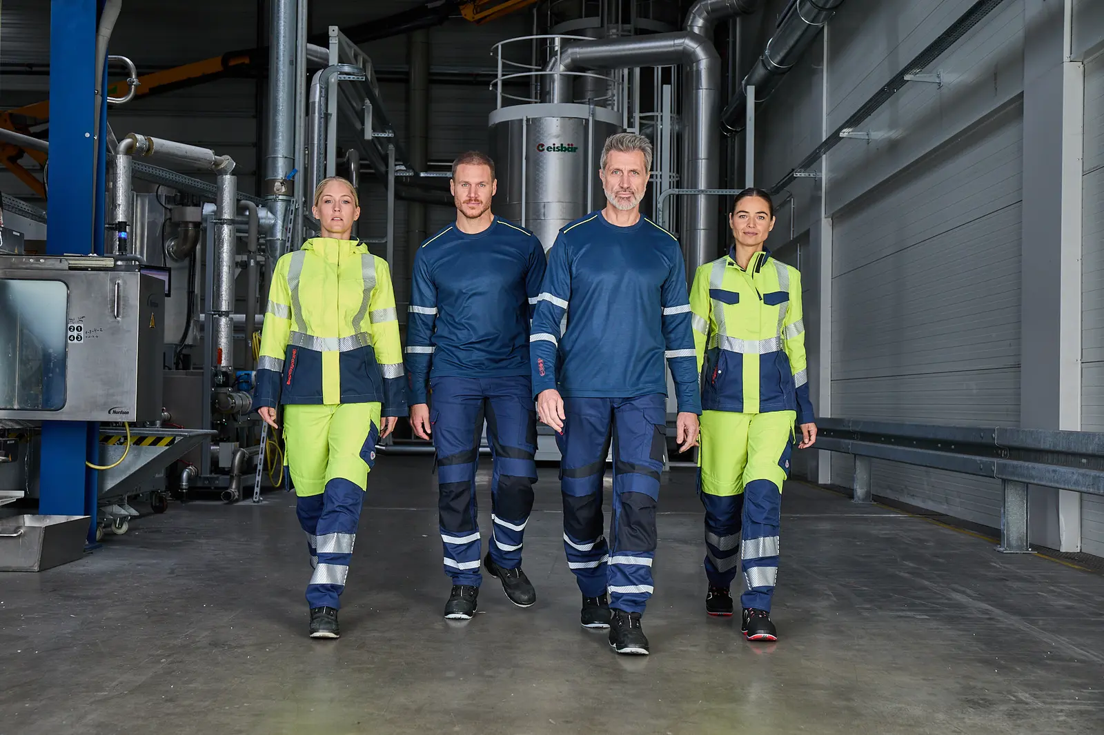 Vier Models in BP-Warnschutzkleidung gehen durch eine Produktionshalle bei Reiling