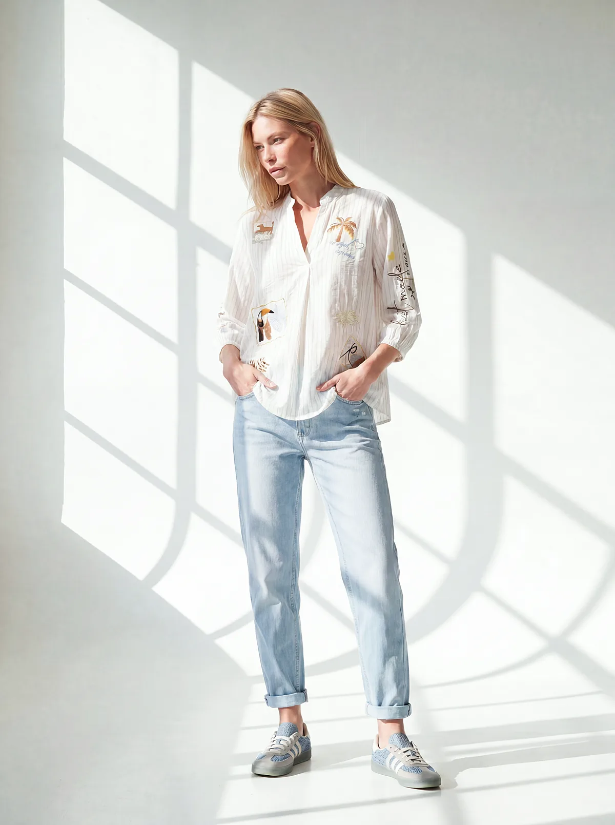 Exklusives KI-Model für RABE trägt bestickte Bluse und Jeans
