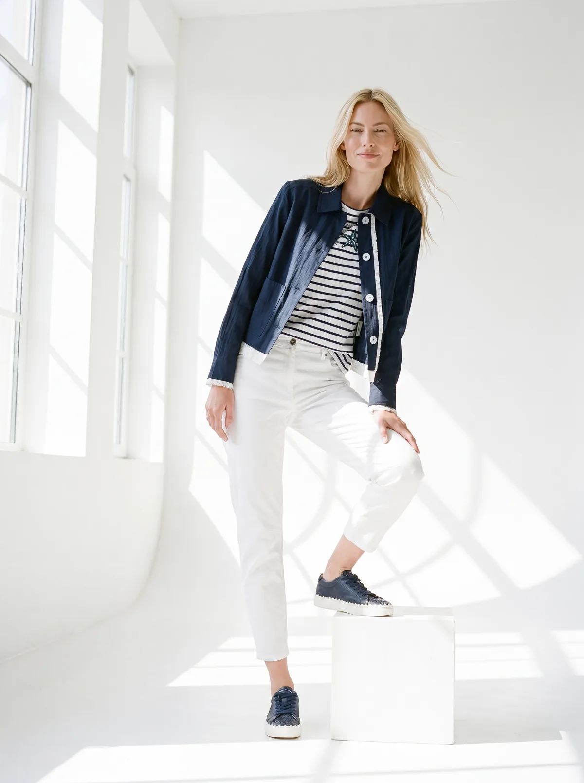 KI-Model trägt die navyblaue Jacke über dem Streifenshirt