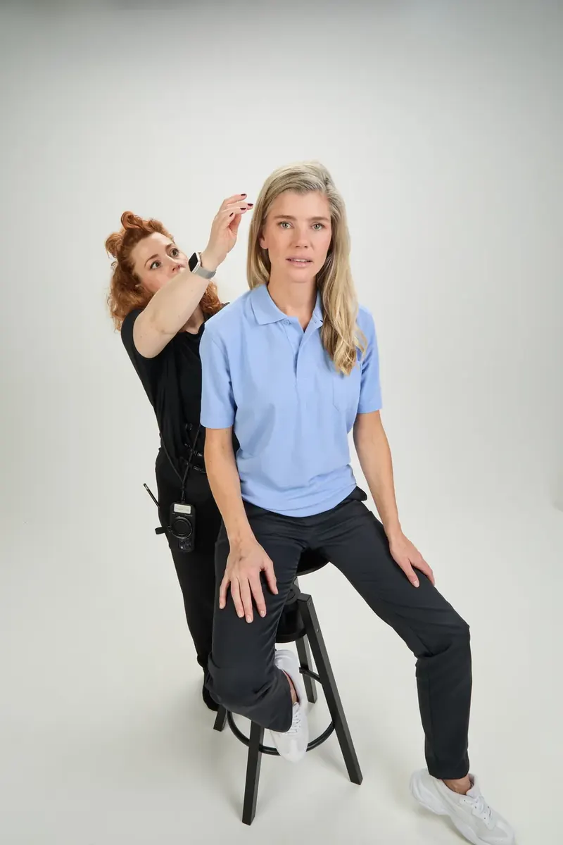 Making-of: Stylistin richtet die Haare eines Models im hellblauen BP-Polo