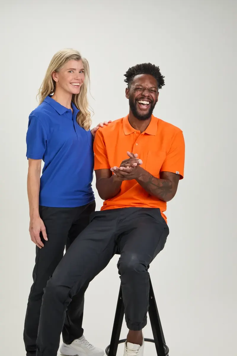 Zwei Models in blauem und orangem BP-Polo lachen zwischen zwei Aufnahmen