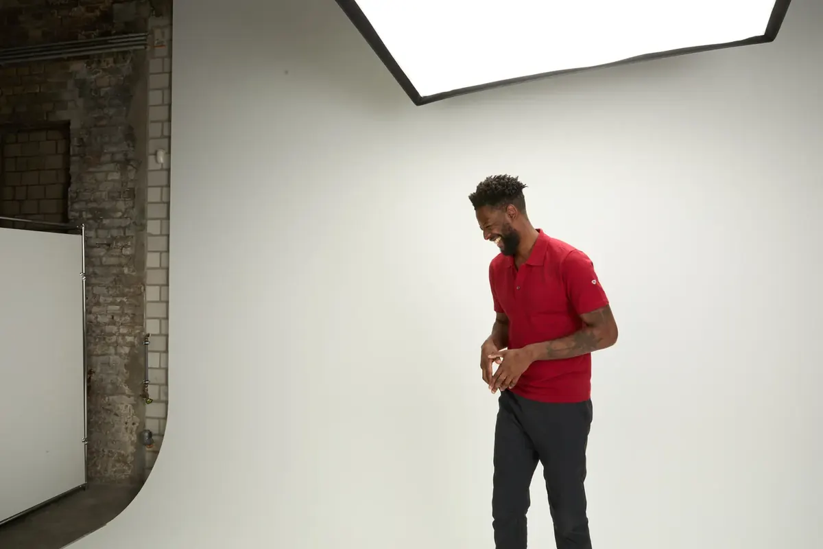 Blick ins Studio mit Backsteinwand: Model im roten BP-Polo vor der weißen Hohlkehle