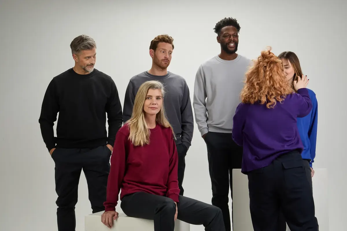 Making-of: Gruppe in farbigen BP-Sweatshirts, die Stylistin richtet ein Oberteil