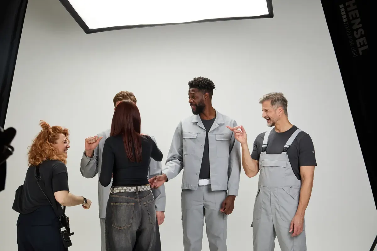 Making-of: Stylistin prüft den Sitz einer grauen BP-Arbeitsjacke am Model