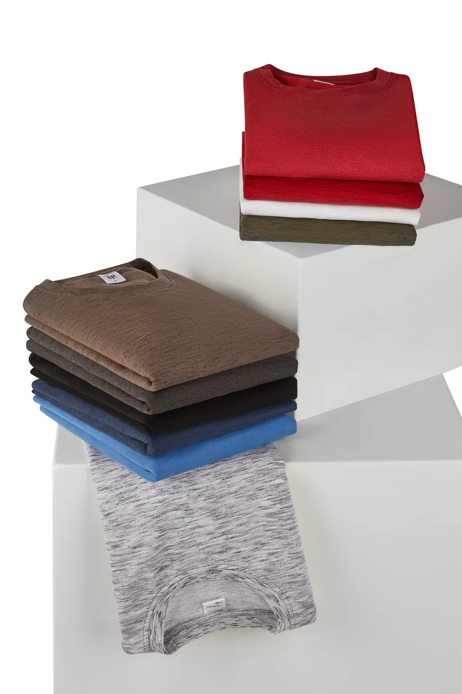 Produktfoto: gefaltete BP-Shirts in mehreren Farben auf weißen Podesten