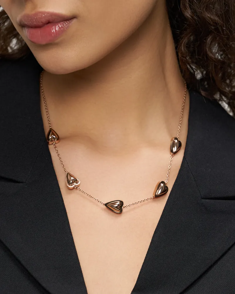 Retuschiertes Schmuckfoto: Model im schwarzen Blazer trägt eine roségoldene Kette mit Herzanhängern